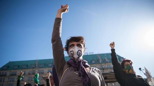 Demonstrantinnen auf der Frauentagsdemo am 8. März 2021 vor dem Brandenburger Tor strecken die Faeuste in die Luft