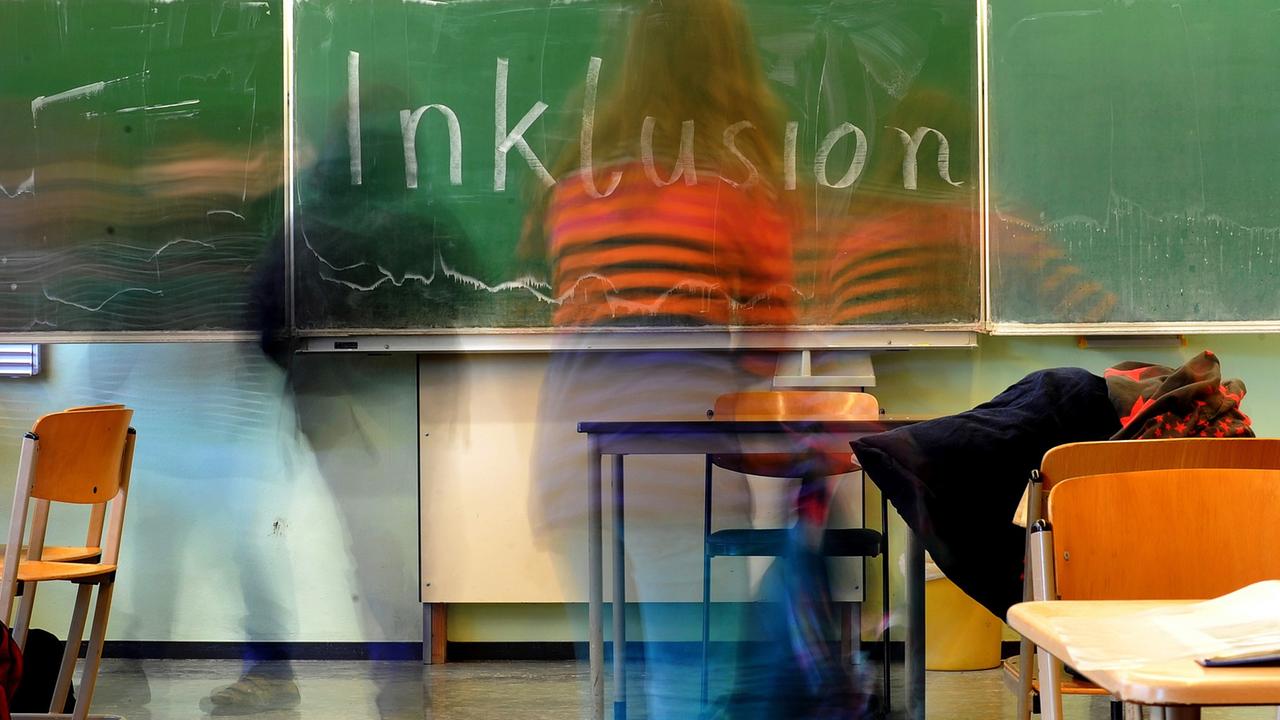 Ein Schulkind steht vor einer Tafel, auf der das Wort "Inklusion" geschrieben steht. Ein Schulkind steht vor einer Tafel, auf der das Wort "Inklusion" geschrieben steht.