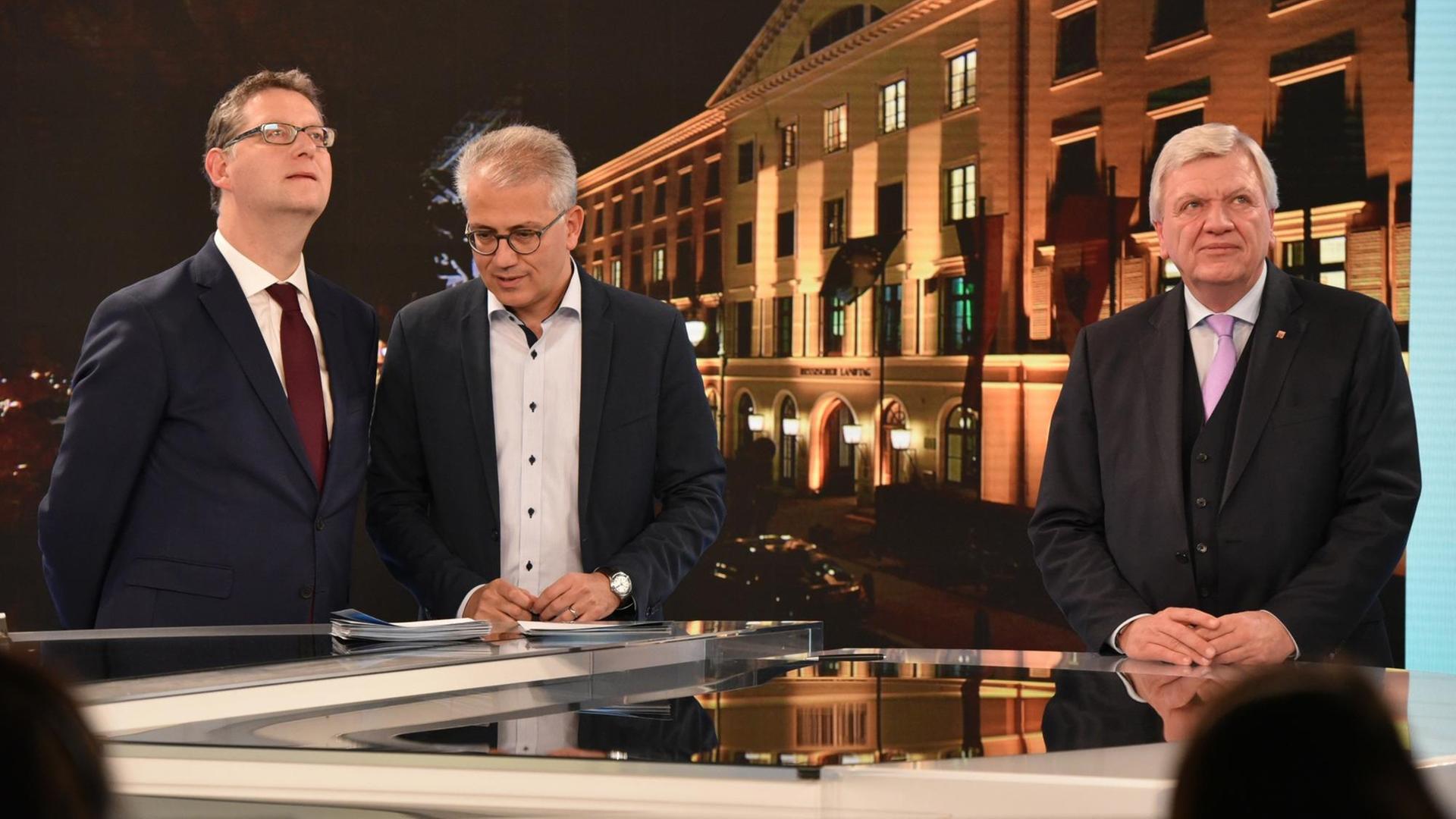 Die Spitzenkandidaten der Parteien, Thorsten Schäfer-Gümbel (SPD), Tarek Al-Wazir (Bündnis90/Die Grünen) und Volker Bouffier (CDU), Ministerpräsident von Hessen, stehen während der HR-Fernsehrunde nebeneinander und schauen auf die Zahlen einer Hochrechnung.