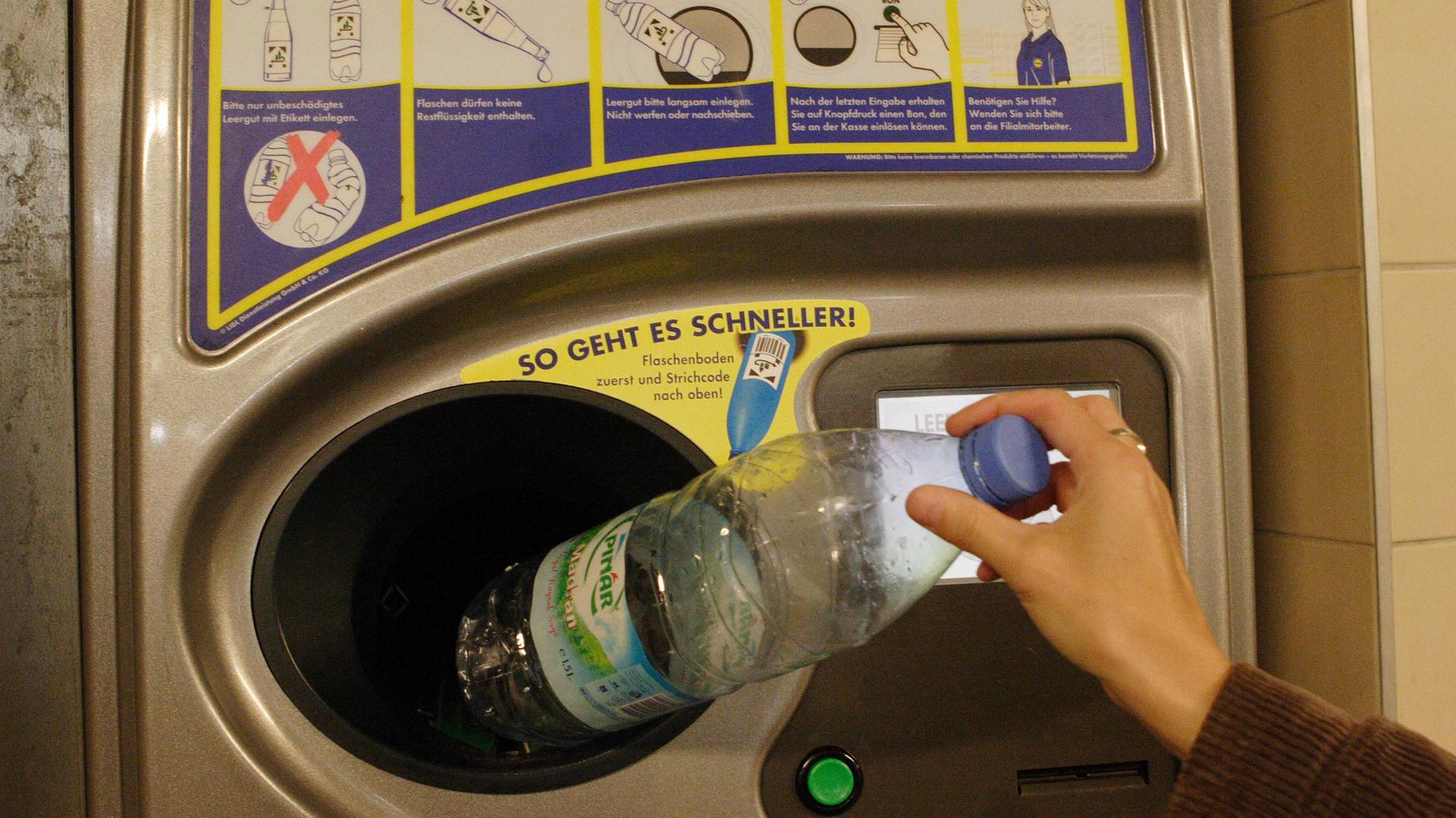 Ein Kundin legt eine PET-Flasche in einen Pfandautomat Ein Kundin legt eine PET-Flasche in einen Pfandautomat