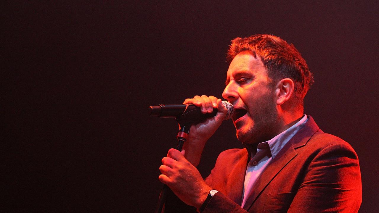 Terry Hall hält sich an einem Mikrofonständer fest, singt Terry Hall hält sich an einem Mikrofonständer fest, singt