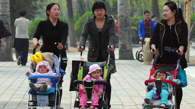 Frauen gehen mit Kinderwagen durch einen Park in Peking.