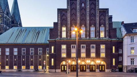 Das Konzerthaus "Die Glocke" in Bremen ist in der Dämmerung erleuchtet. Auf der Backsteinaußenwand steht "Die Glocke"