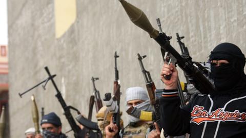 Bewaffnete Terroristen richten Maschinengewehre in die Höhe