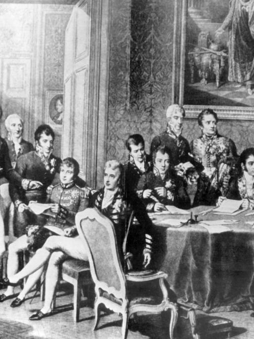 Der österreichische Staatsmann versuchte durch Kongreßdiplomatie, die vorrevolutionäre politische und soziale Ordnung in Europa wiederherzustellen. Er bekämpfte alle liberalen und revolutionären Bewegungen. Klemens Wenzel Fürst von Metternich wurde am 15. Mai 1773 in Koblenz geboren und ist am 11. Juni 1859 in Wien gestorben. Die zeitgenössische Darstellung zeigt stehend (l-r): Wellington, Lobo da Silveira, Saldanha da Gama, Löwenhjelm, Noailles, Metternich, La Tour du Pin, Nesselrode, Dalberg, Rasumofsky, Stewart, Clancarty, Wacken, Gentz, Humbold, Cathcart sowie sitzend (l-r): Hardenberg, Palmella, Castlereagh, Wessenberg, Labrador, Talleyrand und Stackelberg.