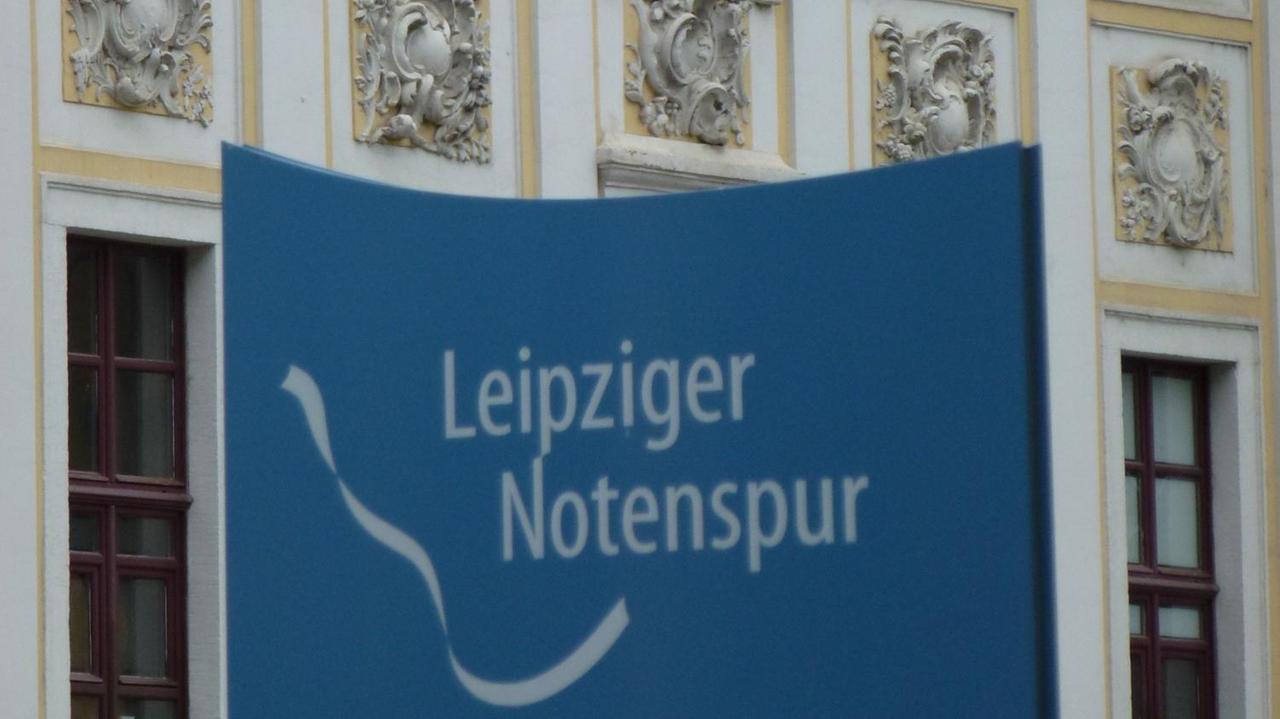 Das weiße Band und der Schriftzug der Notenspur auf einer blauen Infosäule in Leipzig. Das weiße Band und der Schriftzug der Notenspur auf einer blauen Infosäule in Leipzig.