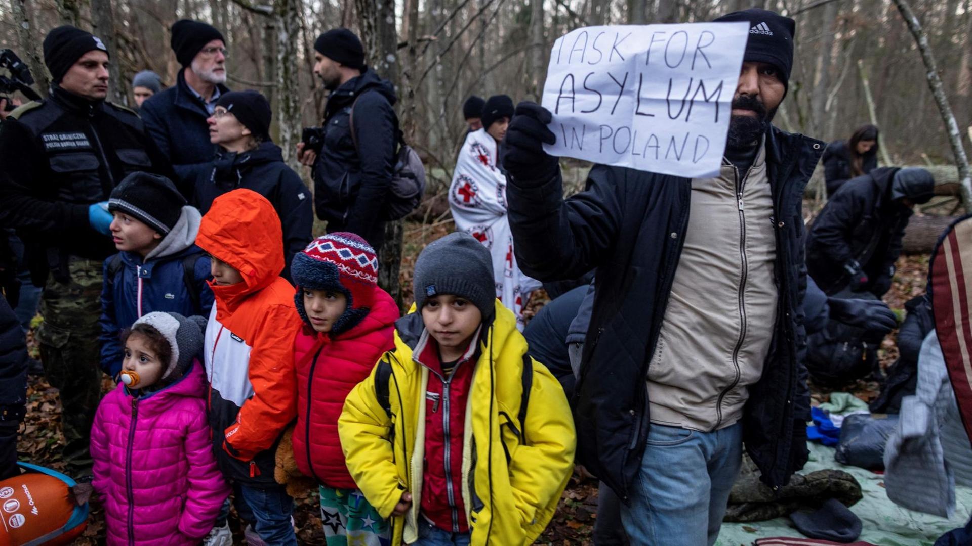 Kurdische Familie aus dem Irak im polnischen Narewka nahe der Grenze zu Belarus mit einem Schild "Ich suche Asyl in Polen"