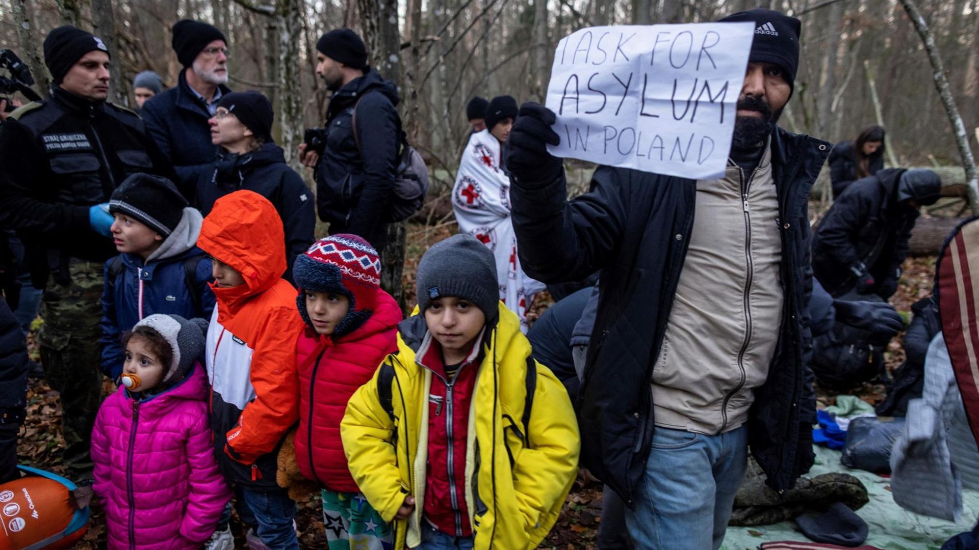 Kurdische Familie aus dem Irak im polnischen Narewka nahe der Grenze zu Belarus mit einem Schild "Ich suche Asyl in Polen" Kurdische Familie aus dem Irak im polnischen Narewka nahe der Grenze zu Belarus mit einem Schild "Ich suche Asyl in Polen"