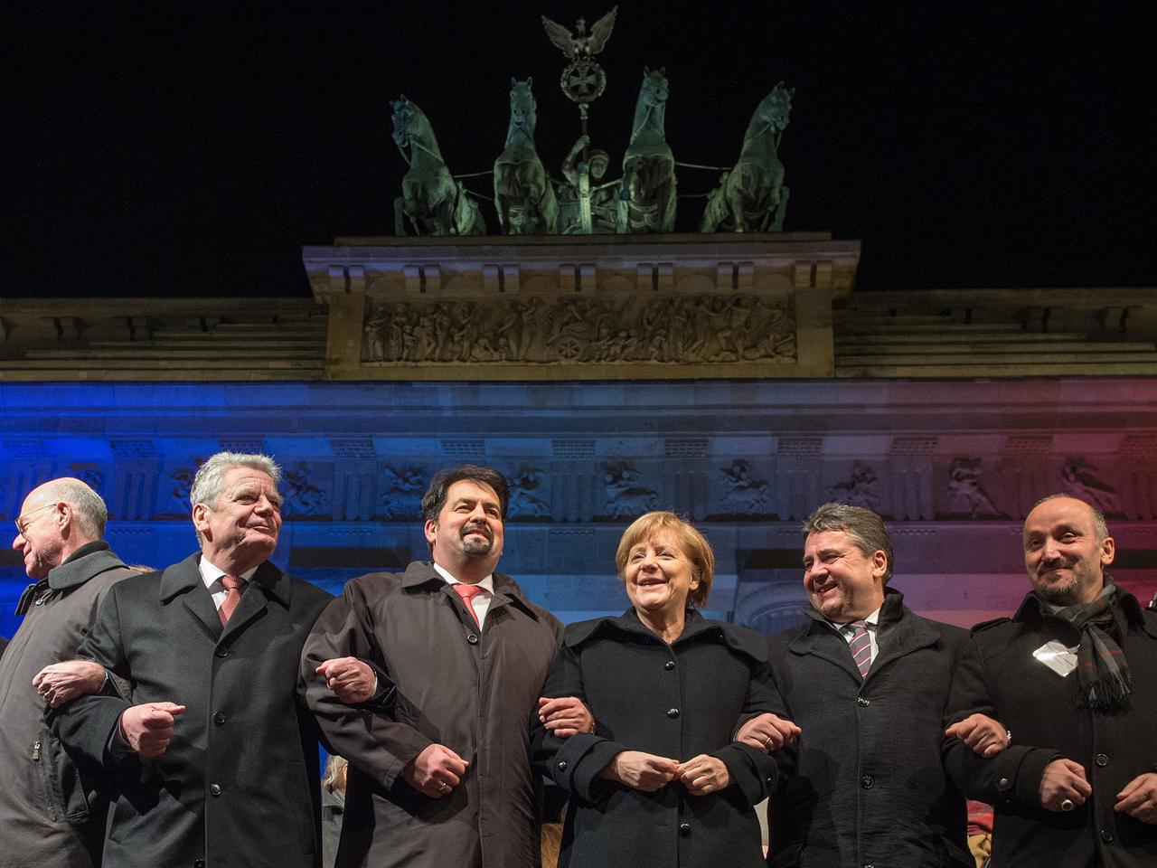 Bundestagspräsident Norbert Lammer (CDU), Bundespräsident Joachim Gauck, der Vorsitzende des Zentralrates der Muslime in Deutschland, Aiman Mazyek, Bundeskanzlerin Angela Merkel (CDU), Bundeswirtschaftsminister Sigmar Gabriel (SPD) und der Vorsitzender der Türkischen Gemeinde zu Berlin, Bekir Yilmaz, haken sich bei einer Mahnwache für die Opfer der Anschläge in Frankreich vor dem Brandenburger Tor in Berlin unter. Bundestagspräsident Norbert Lammer (CDU), Bundespräsident Joachim Gauck, der Vorsitzende des Zentralrates der Muslime in Deutschland, Aiman Mazyek, Bundeskanzlerin Angela Merkel (CDU), Bundeswirtschaftsminister Sigmar Gabriel (SPD) und der Vorsitzender der Türkischen Gemeinde zu Berlin, Bekir Yilmaz, haken sich bei einer Mahnwache für die Opfer der Anschläge in Frankreich vor dem Brandenburger Tor in Berlin unter.