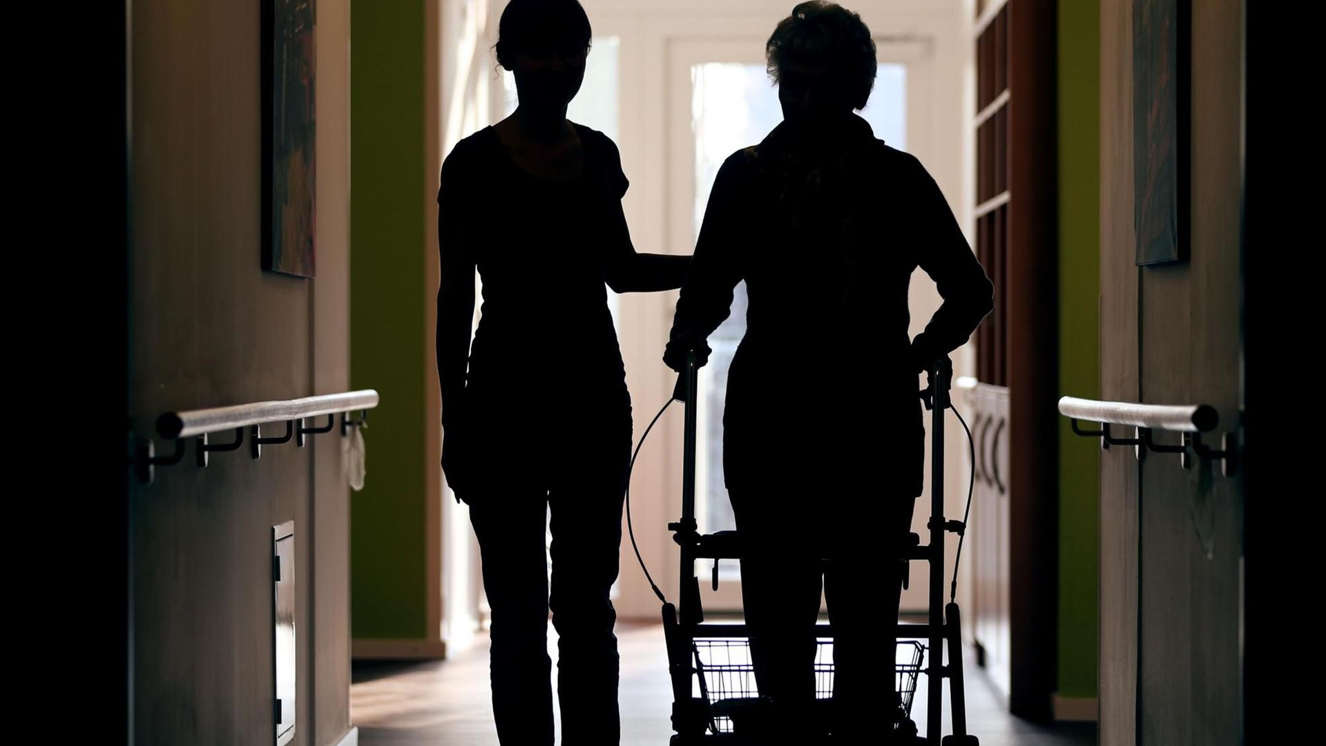 Eine Pflegekraft (l) begleitet am 22.02.2013 die Bewohnerin eines Altenheims mit Rollator beim Gang über den Flur. Eine Pflegekraft (l) begleitet am 22.02.2013 die Bewohnerin eines Altenheims mit Rollator beim Gang über den Flur.
