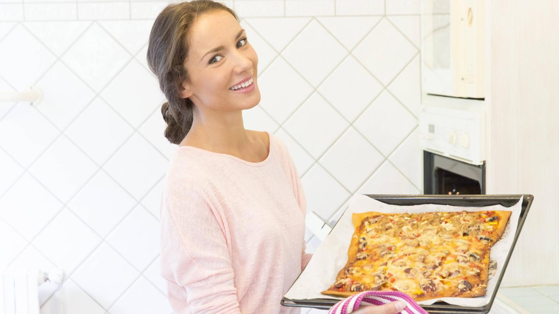Eine Frau backt in ihrer Küche Pizza. Eine Frau backt in ihrer Küche Pizza.