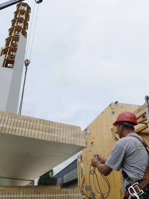 Ein Bauarbeiter richtet ein Paneel für die Windkraftanlage aus Holz auf.
