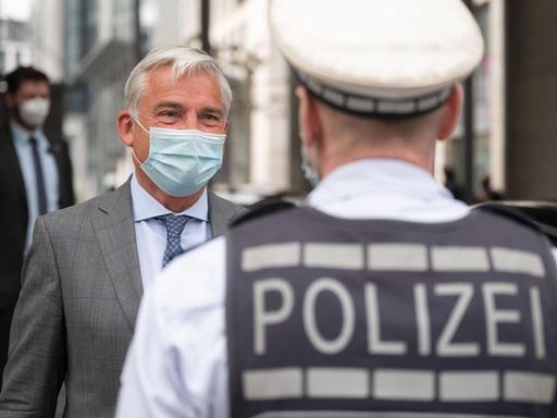 Thomas Strobl (CDU, l), Innenminister von Baden-Württemberg, unterhält sich mit einem Polizisten.