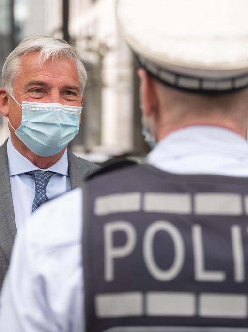 Thomas Strobl (CDU, l), Innenminister von Baden-Württemberg, unterhält sich mit einem Polizisten.