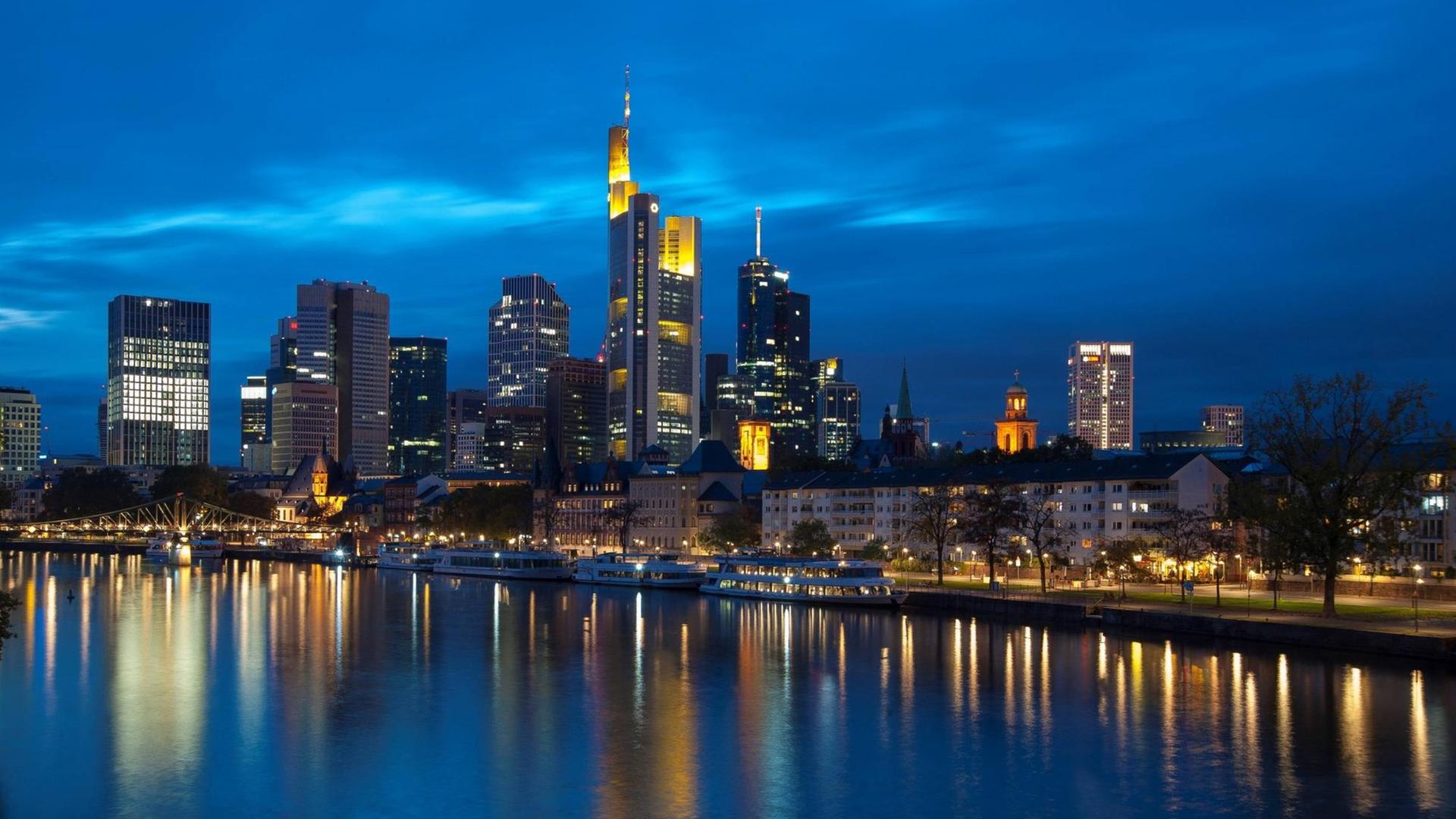Die beleuchteten Hochhäuser von Frankurt am Main spiegeln sich nachts im Fluss Die beleuchteten Hochhäuser von Frankurt am Main spiegeln sich nachts im Fluss
