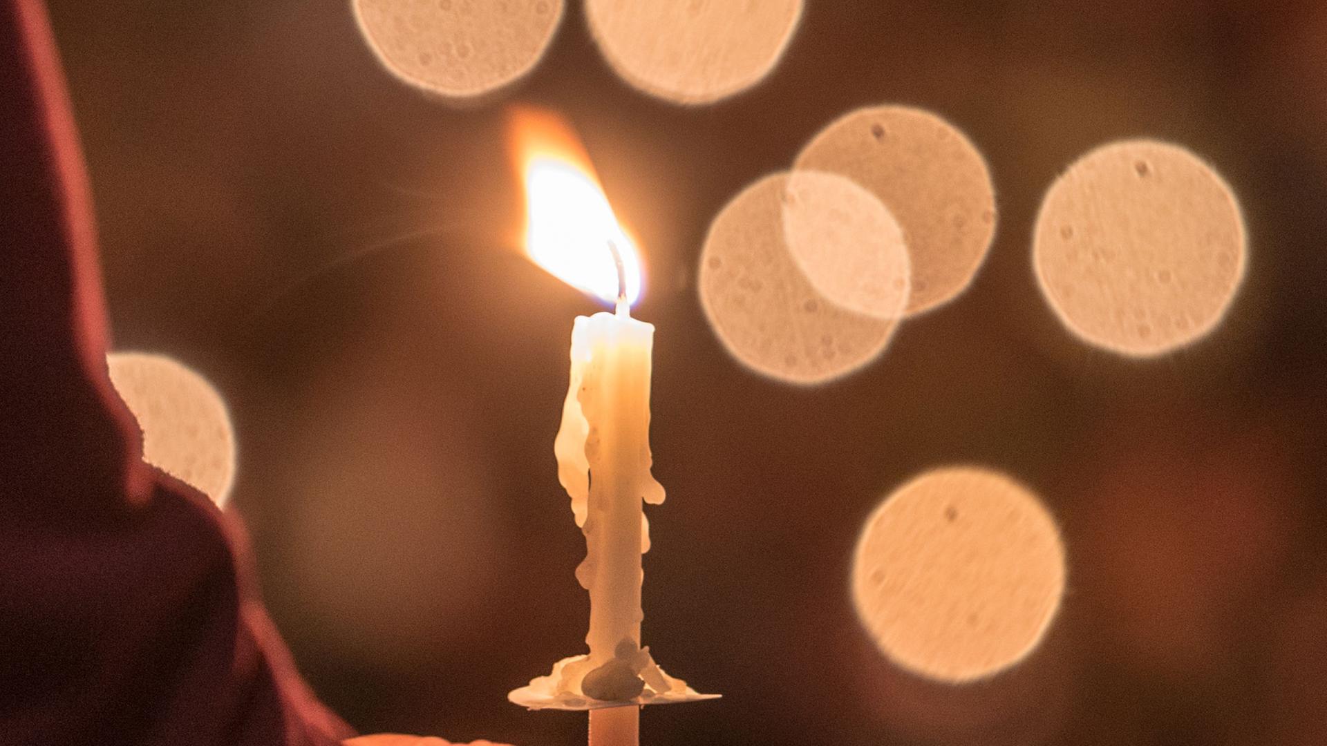 Eine Gläubige hält eine brennende Kerze. Eine Gläubige hält eine brennende Kerze.