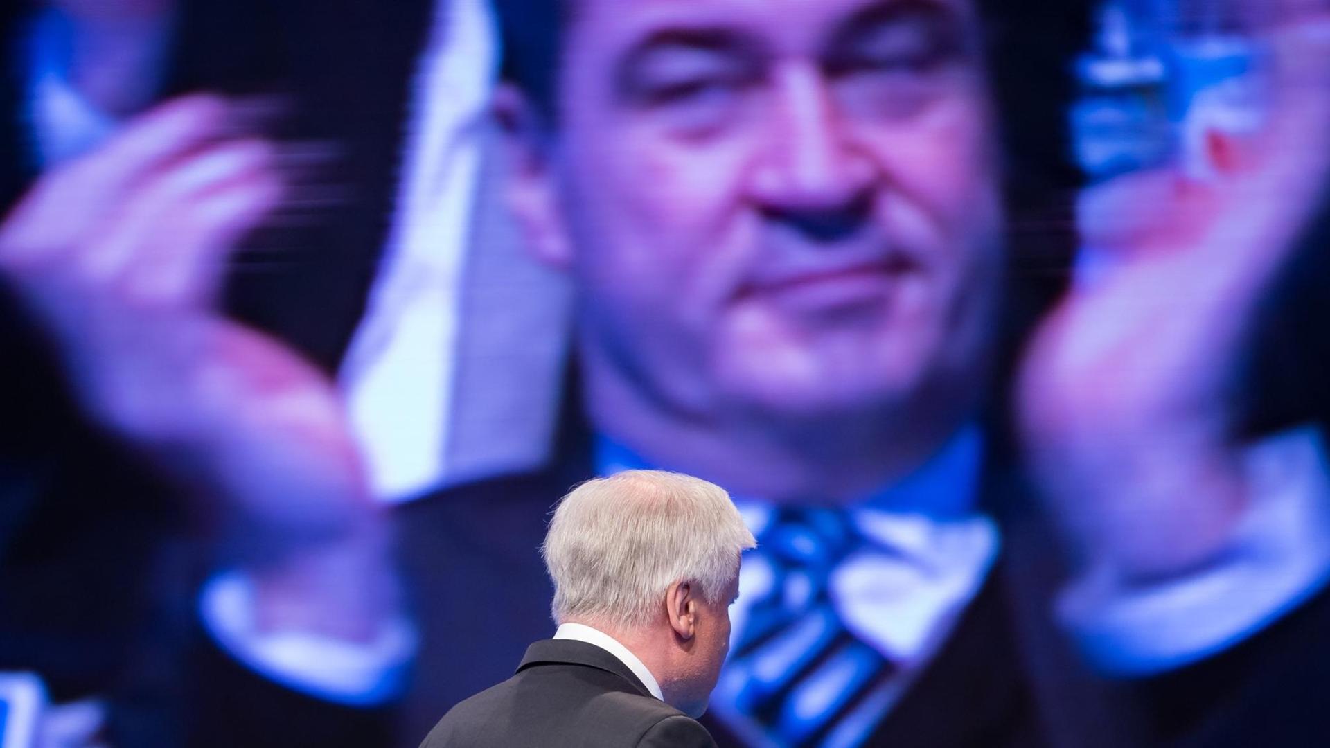 Der CSU-Parteivorsitzende Horst Seehofer verlässt während eines Parteitags die Bühne, auf dem Bildschirm im Hintergrund ist der applaudierende bayerische Finanzminister Markus Söder zu sehen. (Archivbild)