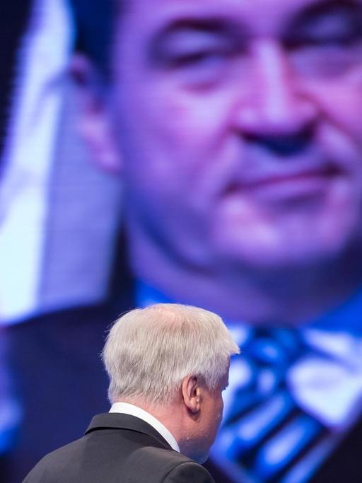 Der CSU-Parteivorsitzende Horst Seehofer verlässt während eines Parteitags die Bühne, auf dem Bildschirm im Hintergrund ist der applaudierende bayerische Finanzminister Markus Söder zu sehen. (Archivbild)