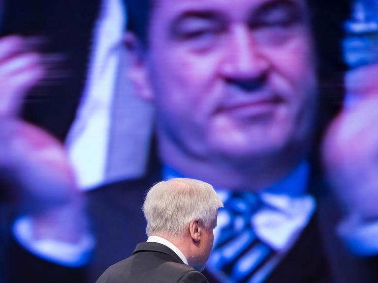 Der CSU-Parteivorsitzende Horst Seehofer verlässt während eines Parteitags die Bühne, auf dem Bildschirm im Hintergrund ist der applaudierende bayerische Finanzminister Markus Söder zu sehen. (Archivbild)