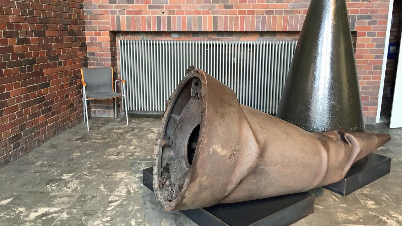 Ein verbeulter Gefechtskopf einer V1 liegt auf einem Sockel in einer Ausstellung Ein verbeulter Gefechtskopf einer V1 liegt auf einem Sockel in einer Ausstellung