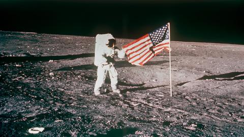 Ein Astronaut der Apollo-12-Besatzung hisst die US-amerikanische Flagge auf dem Mond.