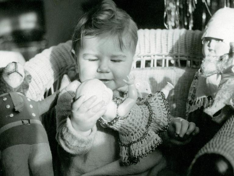 Ein kleines Mädchen spielt 1942 mit ihren Puppen und einem Teddy.