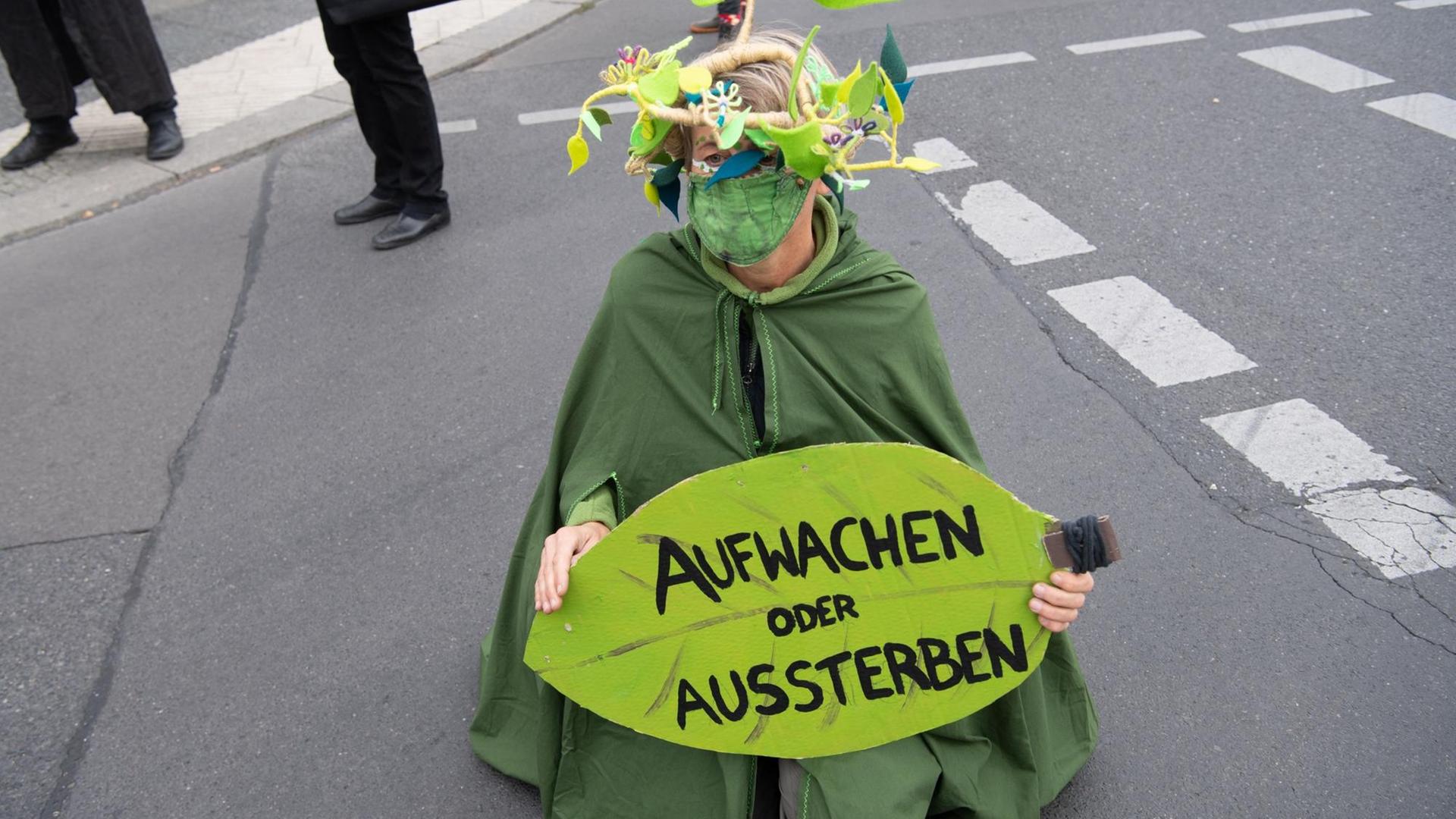 05.10.2020, Berlin: Eine Umweltaktivistin hält während einer Demonstration unter dem Motto «Trauerzug der toten Bäume» von Extinction Rebellion (XR) unweit des Bundeslandwirtschaftsministeriums ein Schild mit der Aufschrift «Aufwachen statt Aussterben». Für diese Woche hat Extinction Rebellion Protestaktionen gegen Umweltzerstörung und Klimawandel angekündigt. Foto: Paul Zinken/dpa 05.10.2020, Berlin: Eine Umweltaktivistin hält während einer Demonstration unter dem Motto «Trauerzug der toten Bäume» von Extinction Rebellion (XR) unweit des Bundeslandwirtschaftsministeriums ein Schild mit der Aufschrift «Aufwachen statt Aussterben». Für diese Woche hat Extinction Rebellion Protestaktionen gegen Umweltzerstörung und Klimawandel angekündigt. Foto: Paul Zinken/dpa