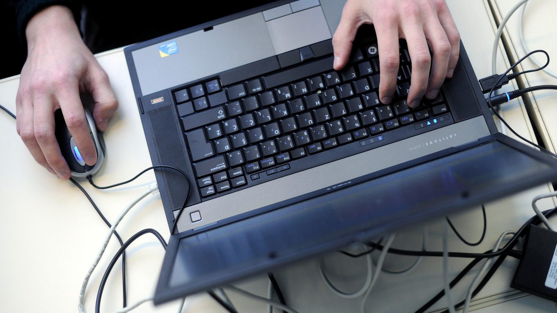 Eine Person bedient einen Laptop mit einer Mouse. Eine Person bedient einen Laptop mit einer Mouse.