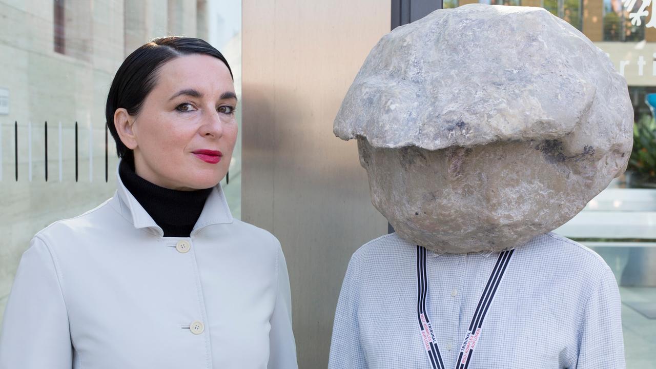 Das Bild zeigt die Künstlerin Natascha Süder Happelmann mit einer Stein-Maske auf dem Kopf. Das Bild zeigt die Künstlerin Natascha Süder Happelmann mit einer Stein-Maske auf dem Kopf.