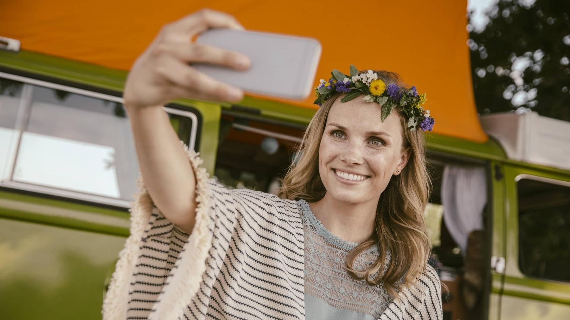 Eine Hippiefrau schießt ein Selfie vor ihrem Reisebus Eine Hippiefrau schießt ein Selfie vor ihrem Reisebus
