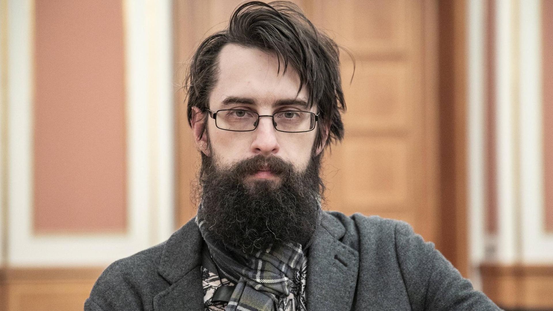 Der Schriftsteller Clemens J. Setz blickt in Richtung des Betrachters. Er trägt Brille und einen Vollbart. Der Schriftsteller Clemens J. Setz blickt in Richtung des Betrachters. Er trägt Brille und einen Vollbart.