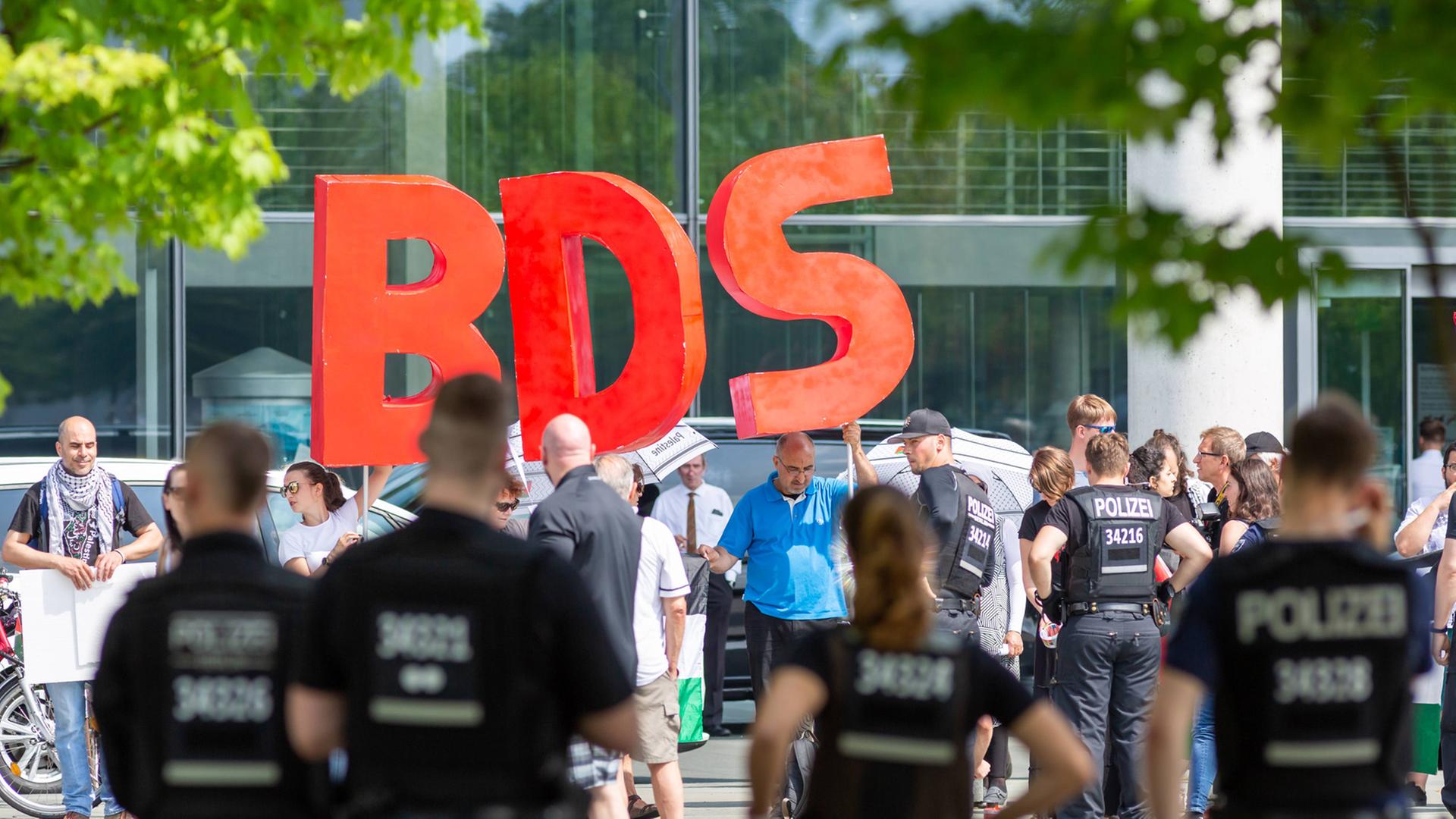 Die Buchstaben BDS - für Boycott, Divestment and Sanctions - werden von Demonstranten hochgehalten, die anlässlich des Besuchs des israelischen Ministerpräsidenten Benjamin Netanjahu im Bundeskanzerlamt in Berlin im Juni 2018 protestierten Die Buchstaben BDS - für Boycott, Divestment and Sanctions - werden von Demonstranten hochgehalten, die anlässlich des Besuchs des israelischen Ministerpräsidenten Benjamin Netanjahu im Bundeskanzerlamt in Berlin im Juni 2018 protestierten