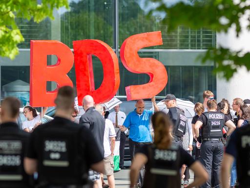 Die Buchstaben BDS - für Boycott, Divestment and Sanctions - werden von Demonstranten hochgehalten, die anlässlich des Besuchs des israelischen Ministerpräsidenten Benjamin Netanjahu im Bundeskanzerlamt in Berlin im Juni 2018 protestierten