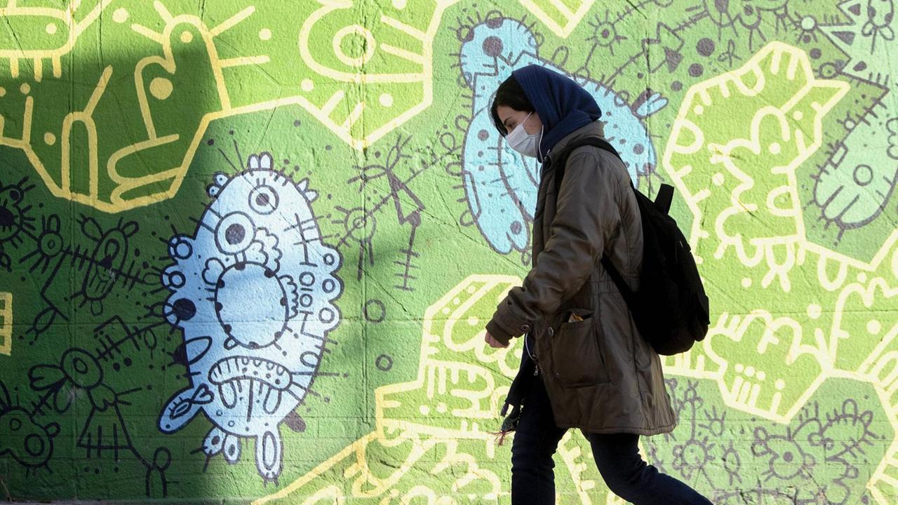 Frau mit Mund-Nasen-Schutz geht durch Teheran. Frau mit Mund-Nasen-Schutz geht durch Teheran.