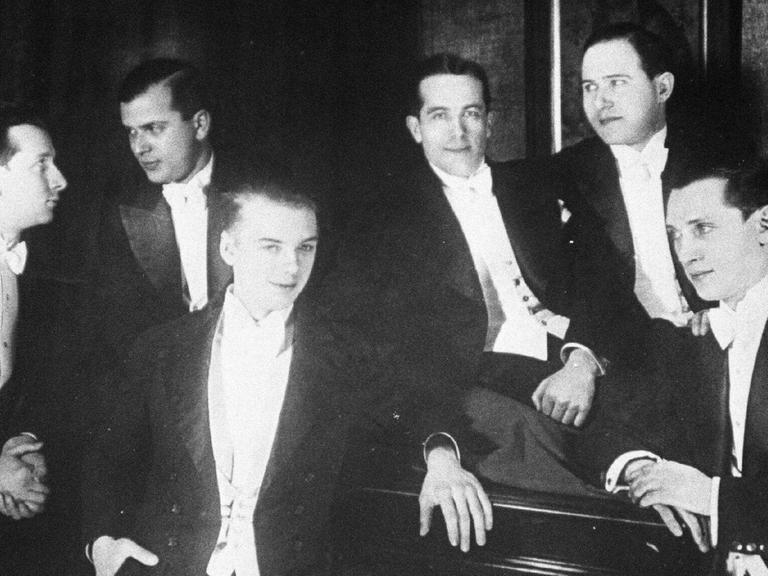 Comedian Harmonists (Ensemble): Ari Leschnikoff (1. Tenor) Erich A. Collin (2. Tenor), Harry Frommermann (3. Tenor), Roman Cycowski (Bariton), Robert Biberti (Bass), Erwin Bootz (Pianist) lehnen lächelnd am Flügel