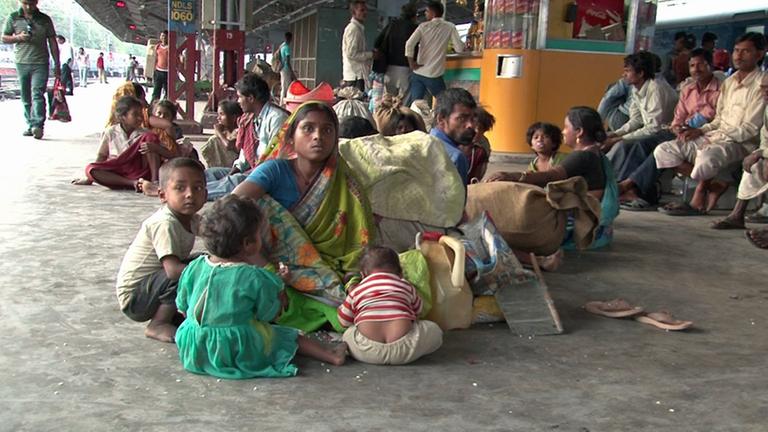Kinder sitzen um ihre Mutter auf dem Boden eines Bahnsteiges in Neu-Delhi. Sie tragen keine Schuhe. Kinder sitzen um ihre Mutter auf dem Boden eines Bahnsteiges in Neu-Delhi. Sie tragen keine Schuhe.