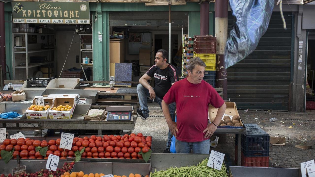 04.07.2019, Griechenland, Athen: Gemüsehändler stehen an ihren Ständen in der Varvakios-Markthalle.