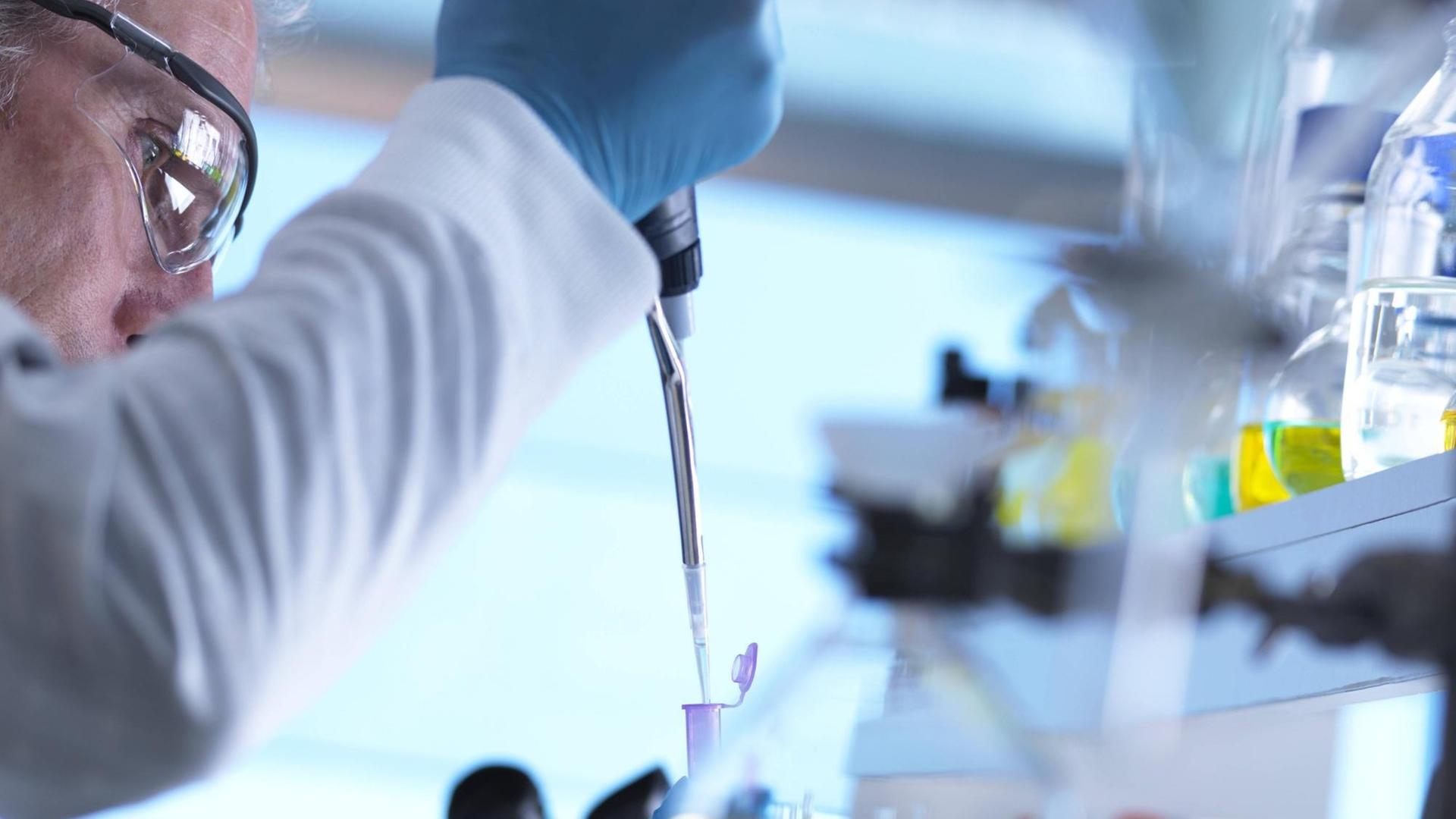 Ein Wissenschaftler nimmt per Pipette eine DNA-Probe Ein Wissenschaftler nimmt per Pipette eine DNA-Probe