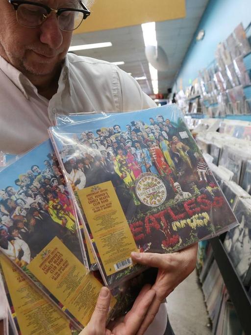 Ein Mitarbeiter eines Plattenladens in University City, Missouri mit der 50. Jubiläumsausgabe von "Sgt. Pepper's" von den Beatles.