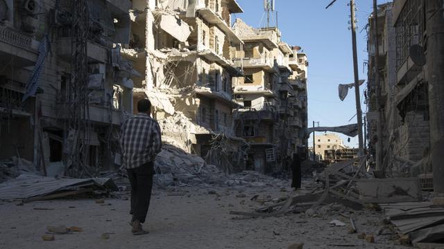 Ein Mann geht durch eine zerstörte Straße in Aleppo
