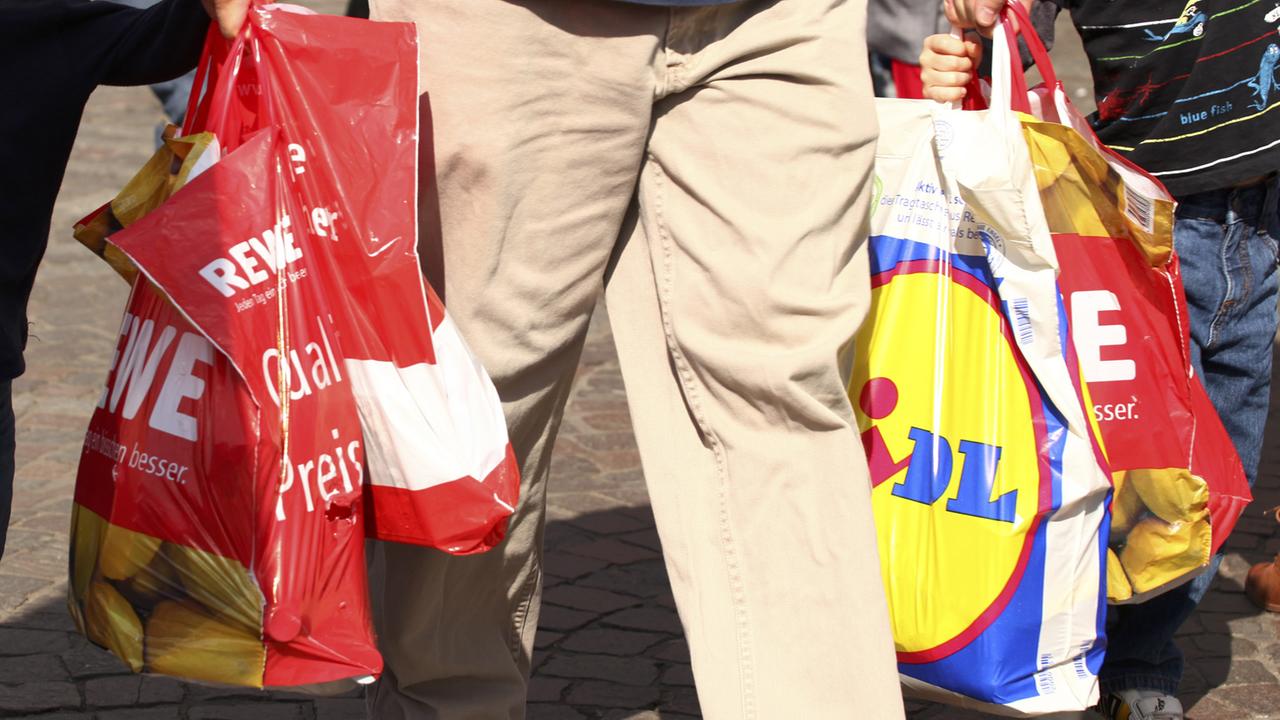 Ein Mann trägt Einkäufe in mehreren Plastiktüten Ein Mann trägt Einkäufe in mehreren Plastiktüten