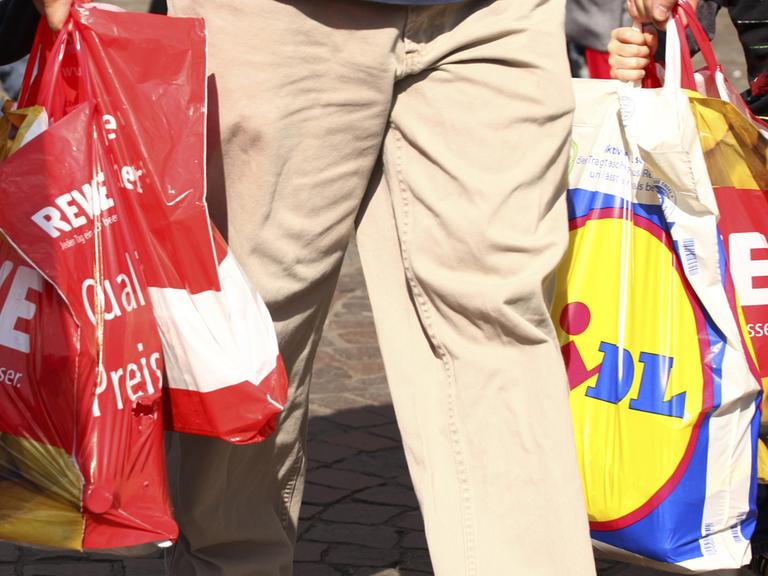 Ein Mann trägt Einkäufe in mehreren Plastiktüten