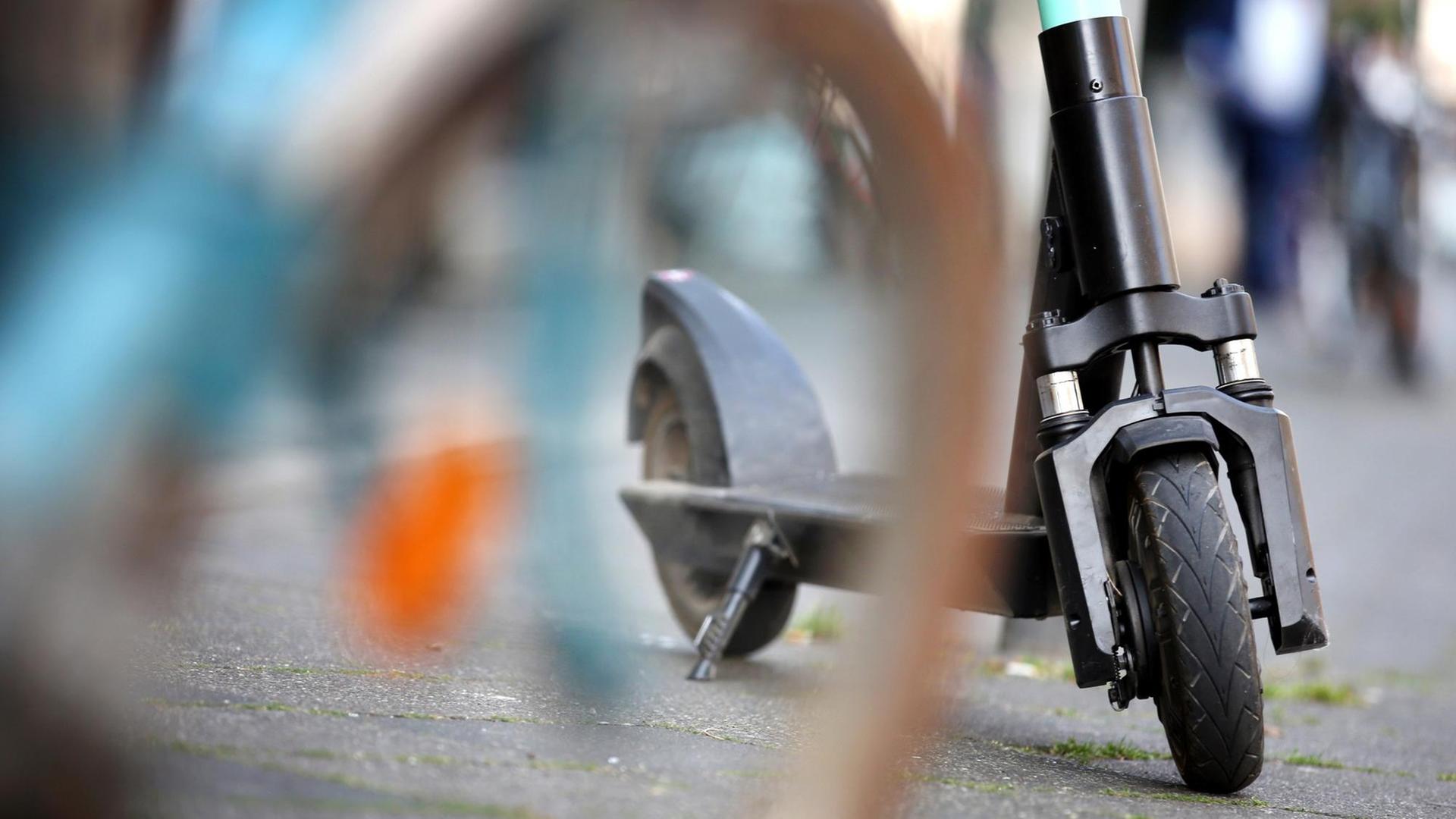 Ein E-Tretroller der Verleihfirma "Tier" steht in der Innenstadt hinter einem abgestellten Fahrrad. Ein E-Tretroller der Verleihfirma "Tier" steht in der Innenstadt hinter einem abgestellten Fahrrad.