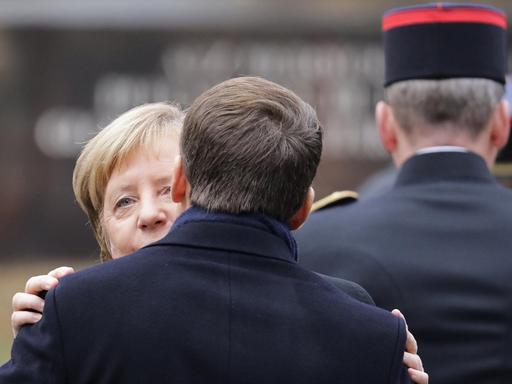 Bundeskanzlerin Merkel und Frankreichs Präsident Macron begrüßen sich.