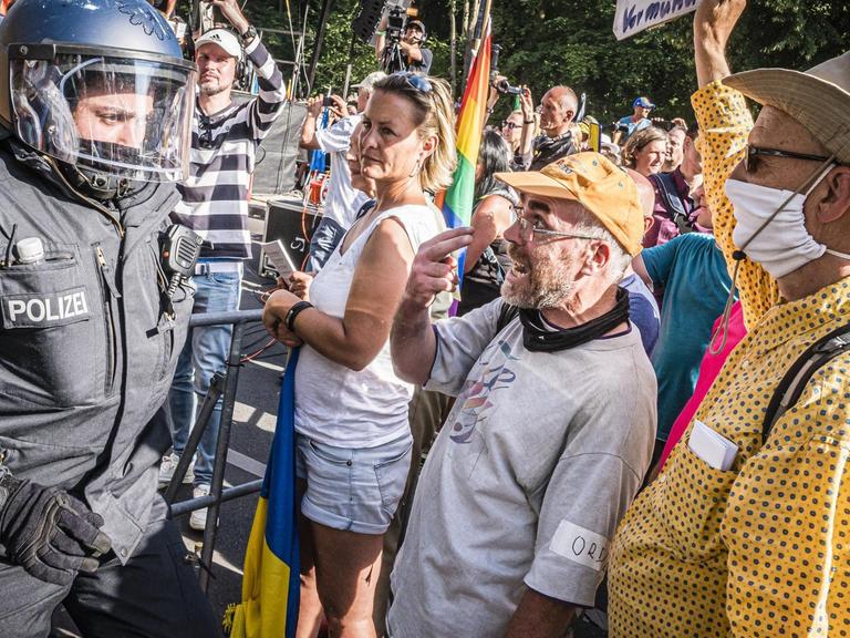 Demonstranten protestieren gegen die Coronamaßnahmen. Daneben stehen Polizisten.