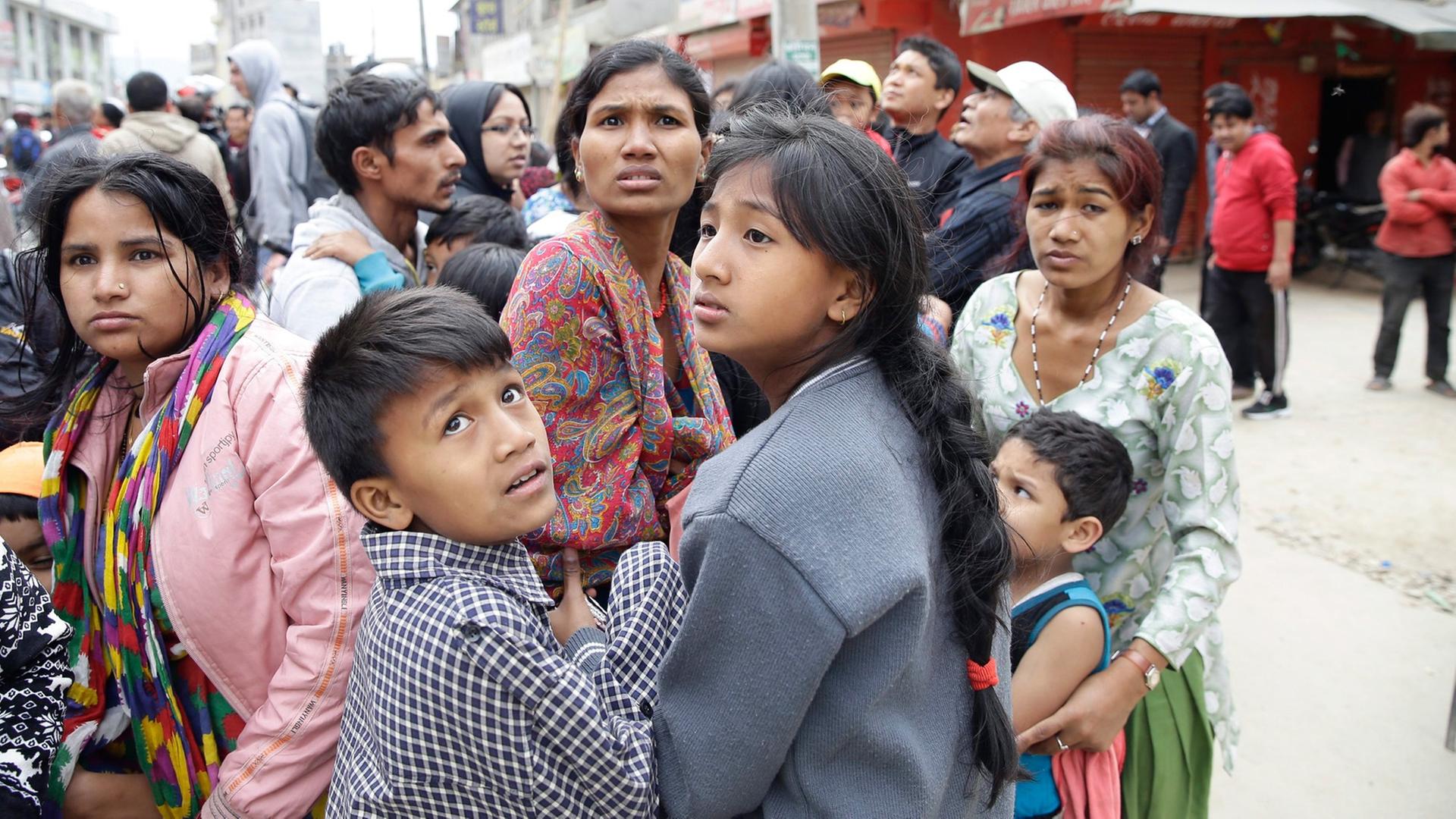 Eine Gruppe Menschen steht verängstigt in einer Straße in Kathmandu. Eine Gruppe Menschen steht verängstigt in einer Straße in Kathmandu.