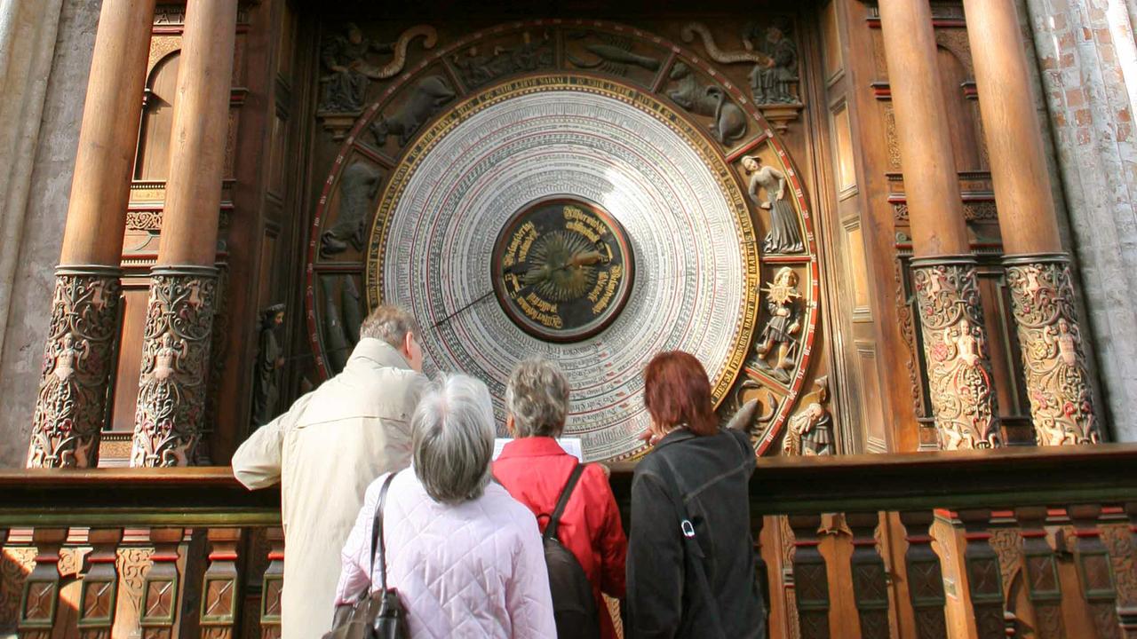 Besucher betrachten die Kalenderscheibe der Astronomischen Uhr in der Marienkirche in Rostock..Die Kalenderscheibe  von 1885 reicht nur bis 2017. 2018 wird sie deshalb ausgewechselt.