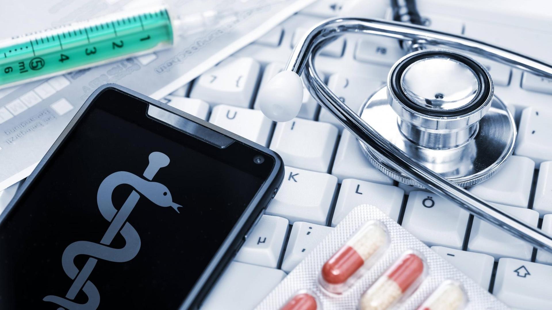 Stethoskop, Computertastatur und Smartphone,