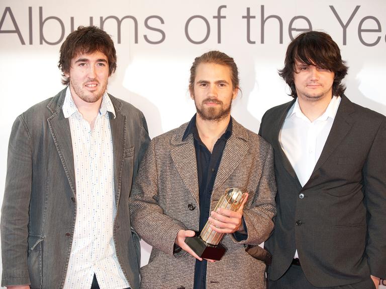 Das Kit Downes Trio hält die Trophäe des  "Mercury Music Prize" in den Händen.