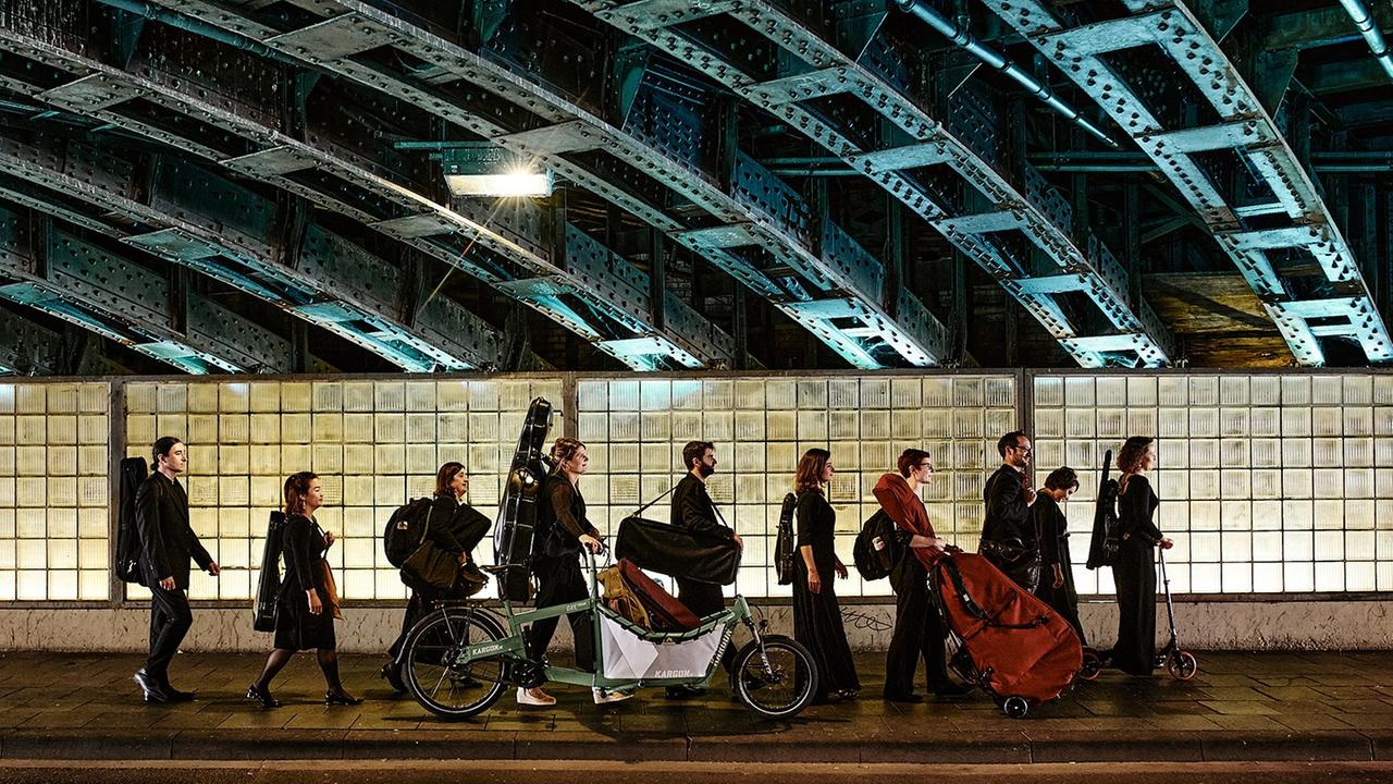 Musiker gehen mit Instrumenten auf einem gestellten Foto durch einen Tunnel. Musiker gehen mit Instrumenten auf einem gestellten Foto durch einen Tunnel.